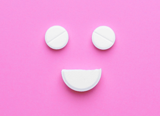 antidepressant pills in the shape of a smiley face on a pink background