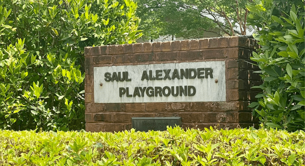 Saul Alexander Playground brick sign amongst bushes and trees
