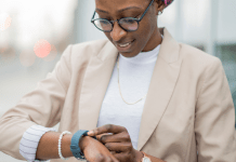 A woman in business clothes looks down at her watch to check her step count.