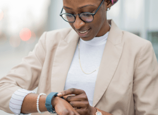 A woman in business clothes looks down at her watch to check her step count.