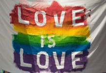 Love is Love spelled out in rainbow colors on a white flag.